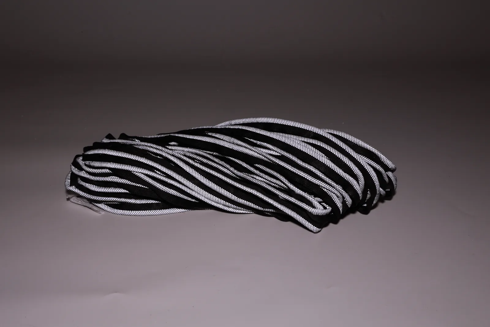 Coiled dark piping with bright patterned edges on a dark background