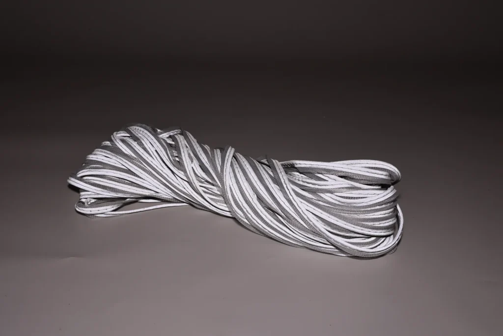 Bundle of silver-gray MP0101 piping with bright reflective edges on a dark background